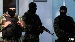 FILE - Armed men stand guard in front of the entrance of the Mejlis of the Crimean Tatar people, the single highest executive-representative body of the Crimean Tatars, in Simferopol, Sept. 16, 2014.