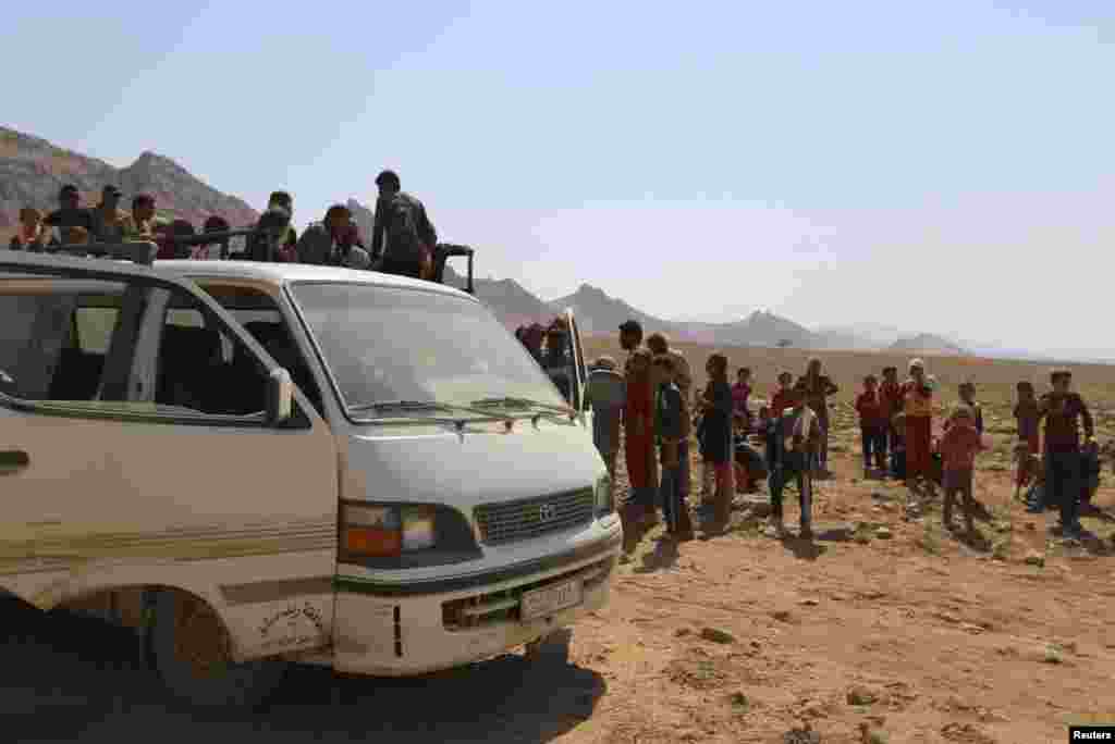 Displaced people from the Yazidi religious minority climb on a truck as they are evacuated from Mount Sinjar with the help of members of the Kurdish People&#39;s Protection Units (YPG), as they make their way towards Newrooz camp, in Syria&#39;s al-Hasakah province, Aug. 13, 2014.