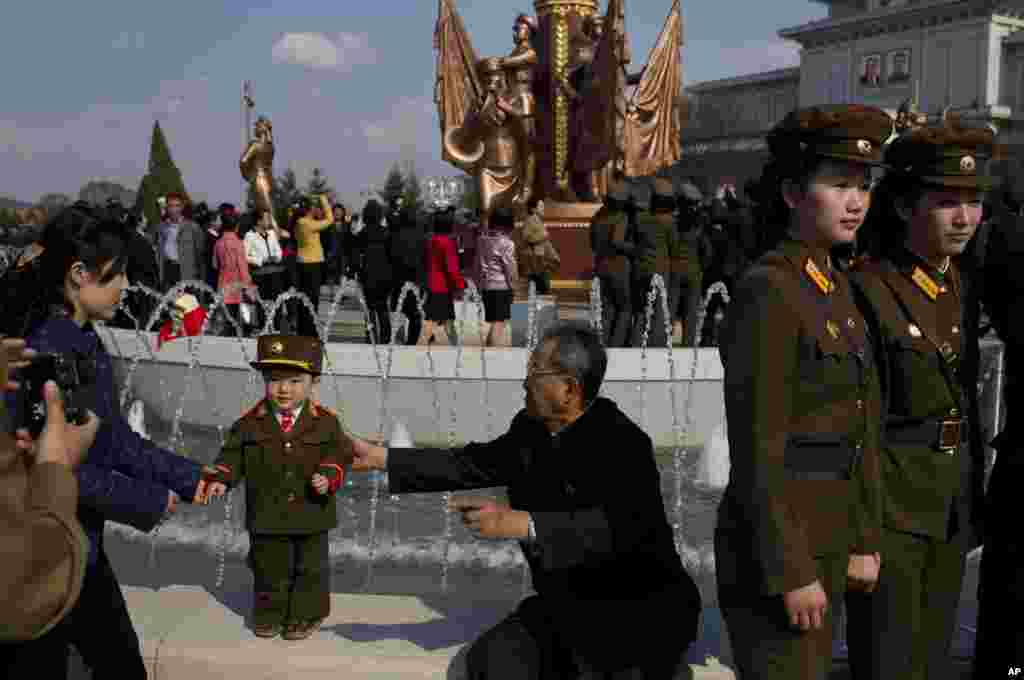 North Korean soldiers and civilians pose for souvenir photos in front of a fountain as they tour the grounds of Kumsusan Palace of the Sun, Pyongyang, April 25, 2013.