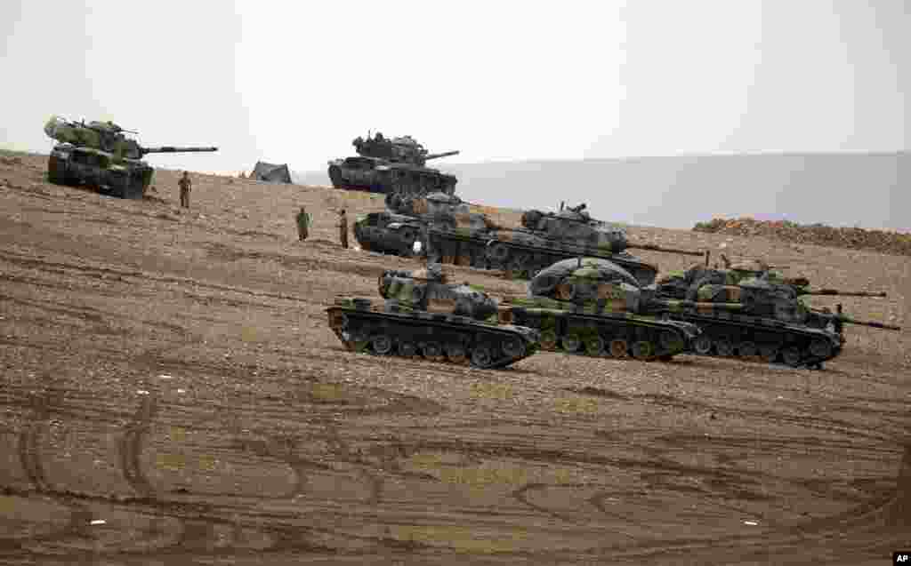 Turkish soldiers hold their positions with their tanks on a hilltop on the outskirts of Suruc, at the Turkey-Syria border, overlooking Kobani, Syria, during fighting between Syrian Kurds and the militants of Islamic State group, Oct. 12, 2014. 