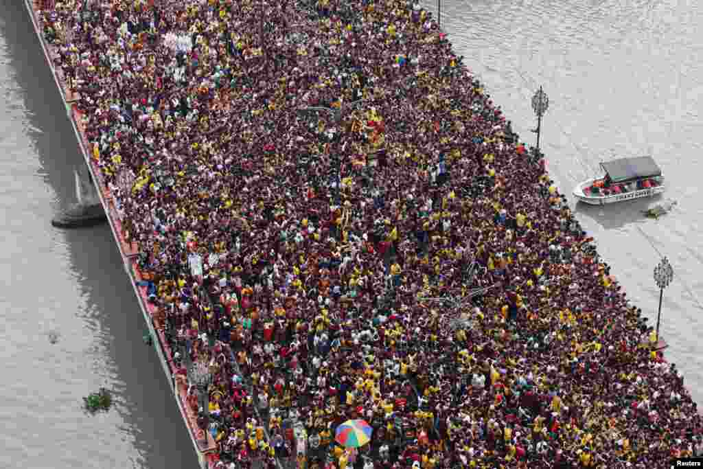 Devotees flock as a carriage bearing an image of Black Nazarene makes its way through the Jones bridge in Manila, Philippines.