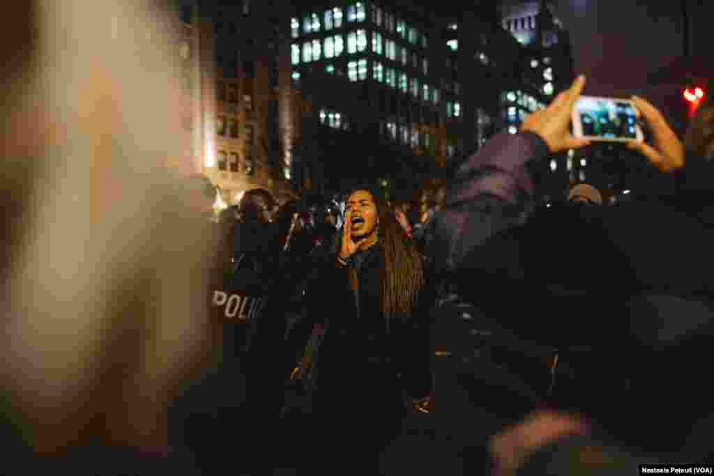 Sur la place Franklin, une jeune femme chante devant la police, à Washington DC, le 20 janvier 2017. (VOA/Nastasia Peteuil)