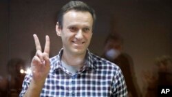 FILE - Jailed Russian opposition leader Alexei Navalny gestures as he stands in a cage in the Babuskinsky District Court in Moscow, Russia, Feb. 20, 2021. 