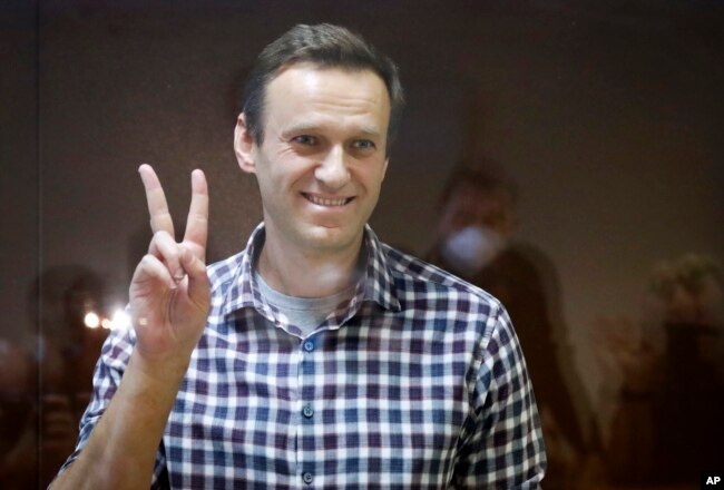 FILE - Russian opposition leader Alexei Navalny gestures as he stands in a cage in the Babuskinsky District Court in Moscow, Russia; Feb. 20, 2021.