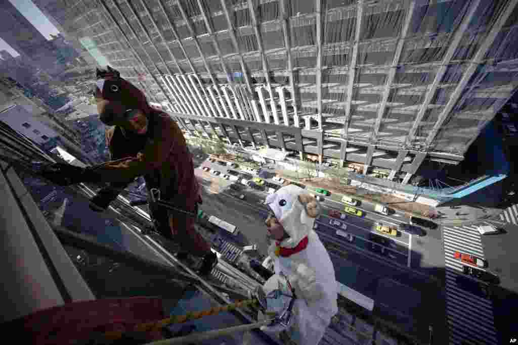 Window cleaners dressed as horse and sheep zodiac animals clean the glass exterior of a hotel in Tokyo. During the year-end &quot;zodiac&quot; event, the outgoing Year of Horse handed a window wiper to the successor Year of Sheep.