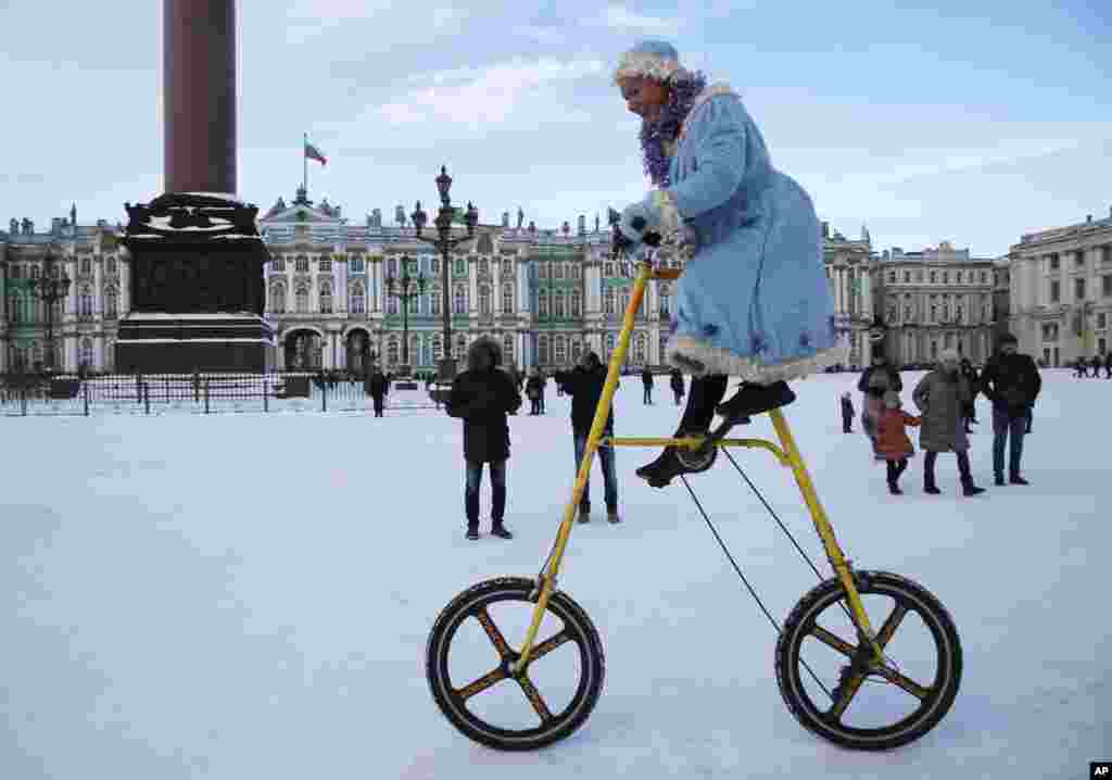 A woman wearing a Snow Maiden costume rides a bike during celebration Old New Year at Dvortsovaya (Palace) Square in St.Petersburg, Russia.