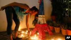 Une française allume des bougies devant une réplique Tour Eiffel à l’extérieur de l'Alliance Français en mémoire des victimes des attaques de Paris, lundi 16 novembre 2015 au quartier financier de Makati City, à l'est de Manille, Philippines.