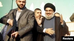 Lebanon's Hezbollah leader Sayyed Hassan Nasrallah (R), escorted by his bodyguards, makes a rare public appearance as he greets his supporters at an anti-U.S. protest in Beirut's southern suburbs September 17, 2012. Nasrallah made a rare public appearance