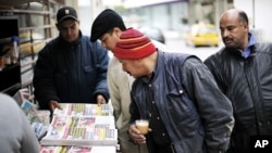 Men look at newspapers at a street kiosk in downtown Tunis, 19 Jan 2011
