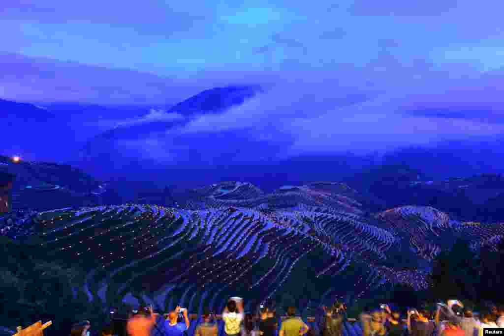 People take pictures of thousands of torches placed in terraced fields during a local festival praying for good harvest at Guilin, Guangxi Zhuang Autonomous Region, China.