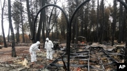 Jerry and Joyce McLean, wearing hazmat suits, look for sentimental items while sifting through the remains of their home, Dec. 5, 2018, in Paradise California.