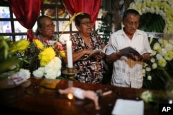 People pray next to the coffin of slain journalist Gumaro Perez during his wake inside his mother's home in Acayucan, Veracruz state, Mexico, Wednesday, Dec. 20, 2017.