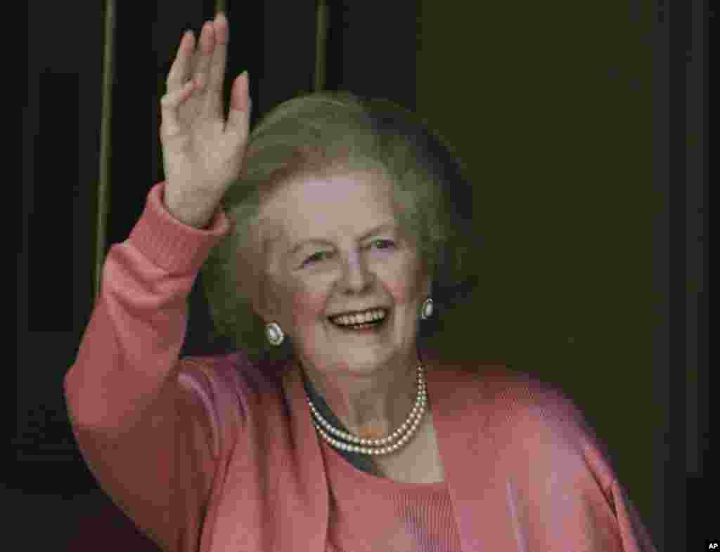 Former British Prime Minister Margaret Thatcher gestured to members of the media as she stands on her house doorstep, following her return home from hospital, in central London, June 29, 2009.