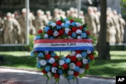 NATO forces stand behind a wreath during a memorial ceremony on the fourteenth anniversary of the 9/11 terrorist attacks on the United States at the headquarters of the International Security Assistance Force, in Kabul, Afghanistan, Sept. 11, 2015.