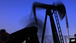 FILE - An oil pump works in the Persian Gulf desert oil field of Sakhir, Bahrain.