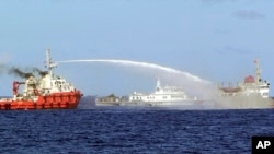 In this photo released by Vietnam Coast Guard, a Chinese ship (L) shoots a water cannon at a Vietnamese vessel (R) while a Chinese Coast Guard ship (C) sails alongside in the South China Sea, off Vietnam's coast, May 7, 2014. 