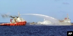 In this photo released by Vietnam Coast Guard, a Chinese ship (L) shoots a water cannon at a Vietnamese vessel (R) while a Chinese Coast Guard ship (C) sails alongside in the South China Sea, off Vietnam's coast, May 7, 2014.