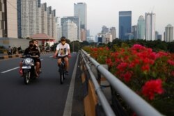 Seorang pria bermasker mengayuh sepeda melalui jalan utama saat pelonggaran pembatasan di tengah pandemi COVID-19, di Jakarta, 28 Juli 2021. (Foto: REUTERS/Willy Kurniawan)