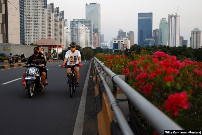 Seorang pria bermasker mengayuh sepeda melalui jalan utama saat pelonggaran pembatasan di tengah pandemi COVID-19, di Jakarta, 28 Juli 2021. (Foto: REUTERS/Willy Kurniawan)