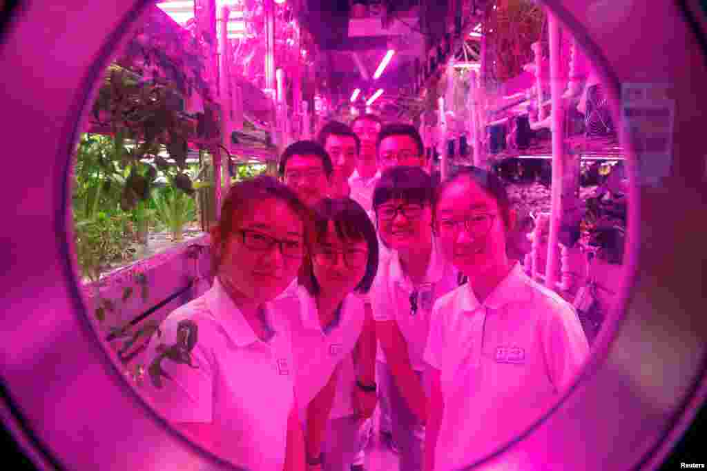 Volunteers smile from inside a simulated space cabin in which they temporarily live as a part of the scientistic Lunar Palace 365 Project, at Beihang University in Beijing, China.