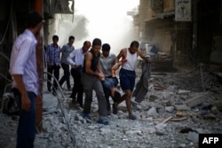 Syrians carry a wounded man following reported air strikes by Syrian government forces on the rebel-held town of Douma, east of the Syrian capital Damascus, on Oct. 2, 2015.