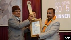 FILE - Nepali Co-operatives and Poverty Alleviation Minister, Chitra Bahadur, left, hands the "Integrity Idol" trophy to civil servant and district administrator, Pradip Raj Kandel during an awards ceremony in Kathmandu, Jan. 10, 2016.