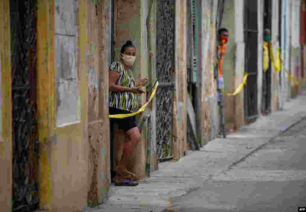 People stand at the door of their houses in a restricted area after cases of COVID-19 were detected in Havana, Cuba, April 7, 2021.