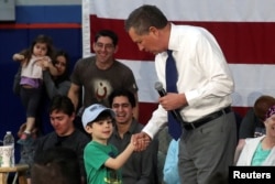 FILE - A boy wearing a Ted Cruz cap shakes hands with U.S. Republican presidential candidate John Kasich during a campaign event in Syracuse, New York, April 18, 2016.