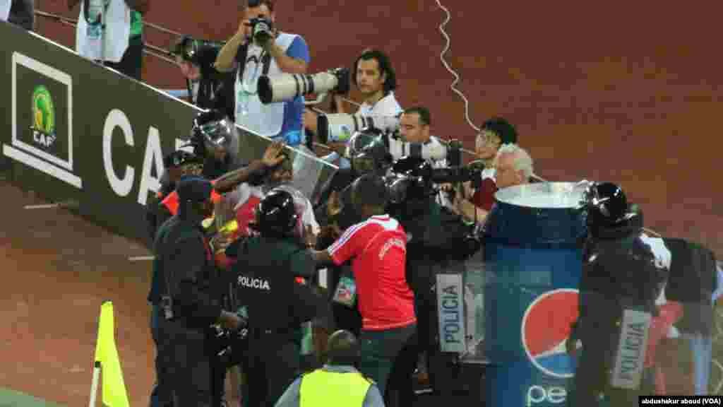 Policiais tentam remover torcedores da Guiné Equatorial que entraram no campo para comemorar após o país marcar um gol contra a Tunísia.