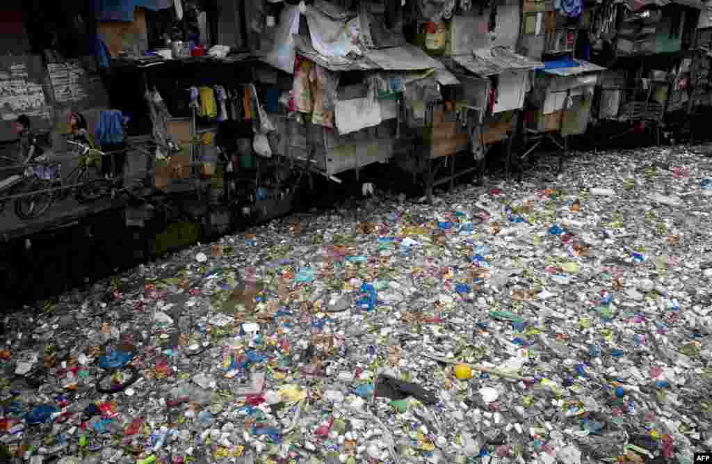 Children walk beside a river filled with garbage in Manila, the Philippines.