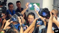 Seorang reporter tak dikenal (tengah), mengangkat senter untuk membaca pernyataan saat berlangsungnya konferensi pers polisi di Hong Kong, Senin, 28 Oktober 2019. 