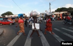 FILE - People cross a road in Monrovia. Despite hundreds of millions of dollars in foreign investment, infrastructure in Liberia remains poor.