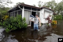 Grady Howell, de Plant City, Florida, ayuda a un amigo a salvar pertenencias de una casa móvil inundada tras el huracán Irma. Sept. 11, 2017.