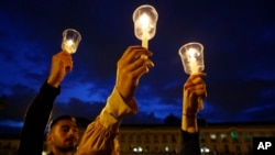 FILE - Demonstrators light candles during a candlelight vigil for slain activists in Bogota, Colombia, July 6, 2018.