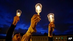 FILE - Demonstrators light candles during a candlelight vigil for slain activists in Bogota, Colombia, July 6, 2018.