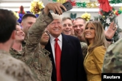 FILE - U.S. President Donald Trump and first lady Melania Trump greet military personnel at the dining facility during an unannounced visit to Al Asad Air Base, Iraq, Dec. 26, 2018.