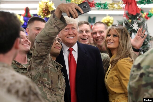 2018年12月26日，美国总统唐纳德·特朗普和第一夫人梅拉尼娅·特朗普在伊拉克的空军基地和美国军人合影。
