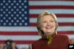 Democratic presidential candidate Hillary Clinton smiles as Democratic vice presidential candidate Sen. Tim Kaine, D-Va., speaks during a campaign event at the Taylor Allderdice High School, Oct. 22, 2016, in Pittsburgh, Pa.