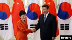 China's President Xi Jinping (R) shakes hands with South Korea's President Park Geun-hye in front of Chinese and South Korean national flags during a meeting at the Great Hall of the People, on the sidelines of the Asia Pacific Economic Cooperation (APEC)