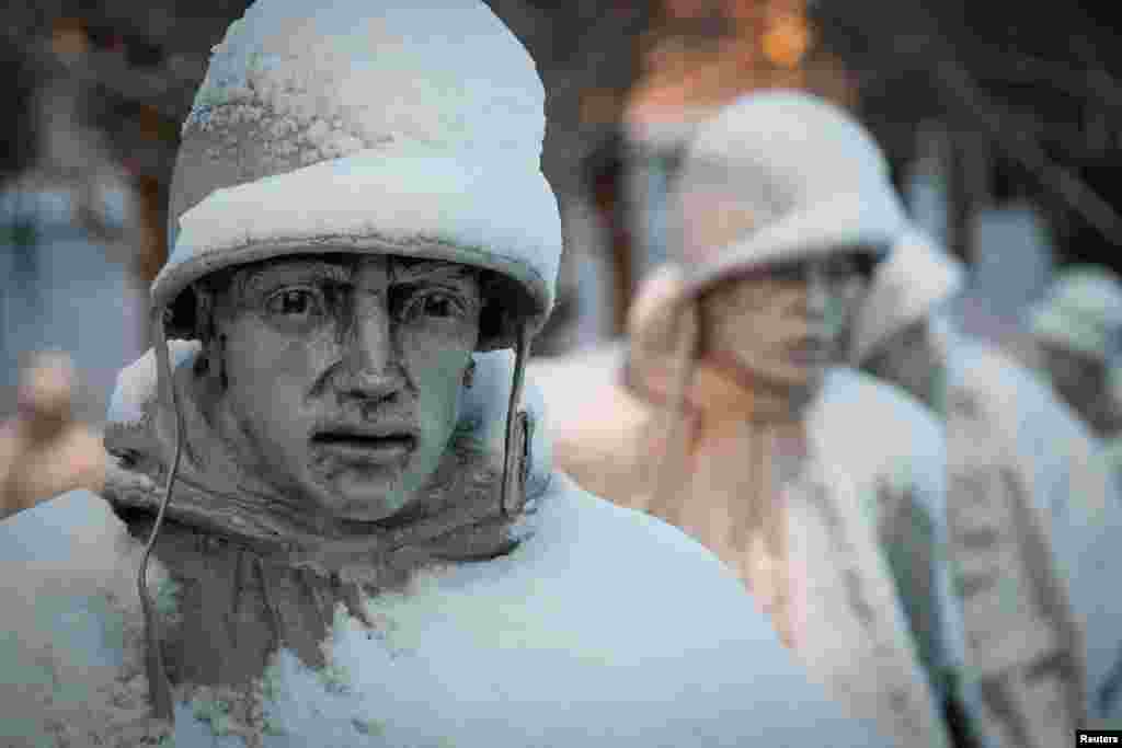 A light dusting of snow from an overnight storm covers the statues at the Korean War Memorial in Washington, D.C. early Friday morning. After a storm blew through the region overnight, roads were being cleared and many schools systems were closed.