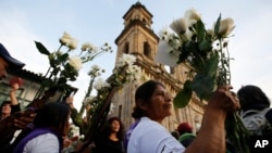 A woman holds flowers as she attends a peace march in Bogota, Colombia, Oct. 12, 2016.