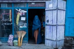 An Afghan woman wearing a burqa exits a small shop in Kabul, Afghanistan, Sunday, Dec. 5, 2021.