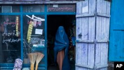 An Afghan woman wearing a burka exits a small shop in Kabul, Afghanistan, Sunday, Dec. 5, 2021.