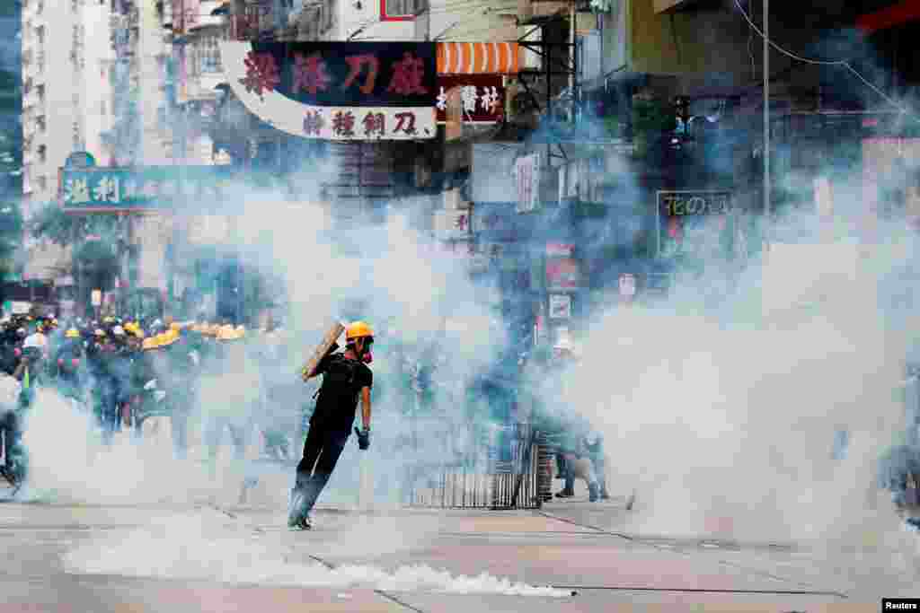 Manifestantes contra la ley de extradición reaccionan a causa de los gases lacrimógenos cuando la policía antidisturbios intenta dispersarlos durante una protesta en Sham Shui Po, en Hong Kong, China, el domingo 11 de agosto.&nbsp;