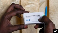 FILE - In this Tuesday, Feb. 23, 2021, photo, a health worker holds a box containing a dose of China's Sinopharm vaccine during the start of the vaccination campaign against the COVID-19 at the Health Ministry in Dakar, Senegal. 