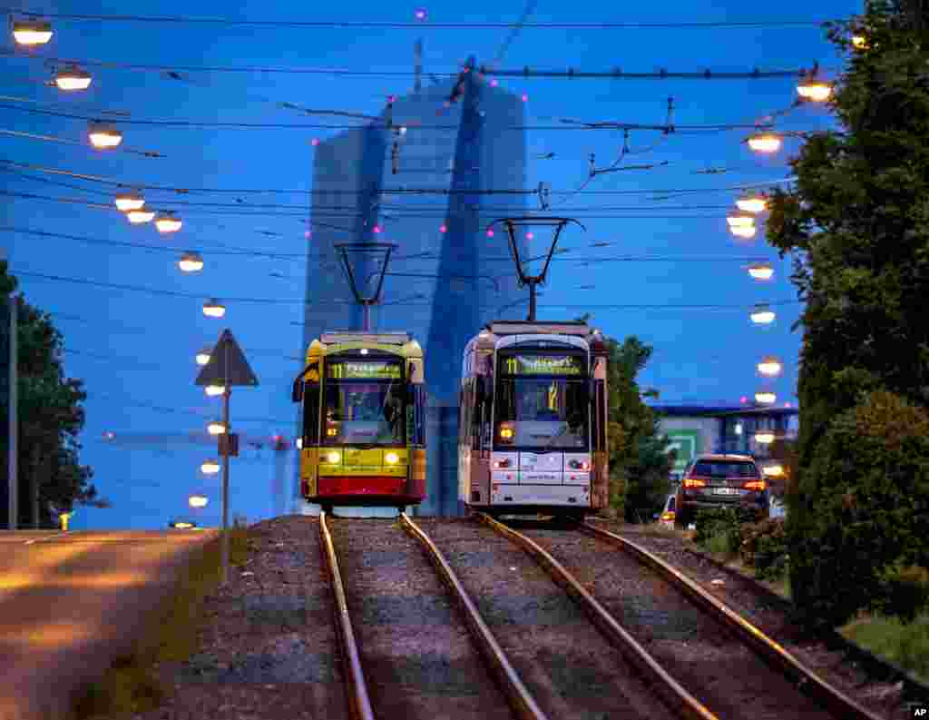 Two trams pass each other in front of the European Central Bank in Frankfurt, Germany.