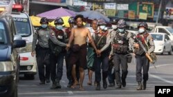 In this file photo taken on February 26, 2021, police march with a resident arrested during a crackdown on protesters holding rallies against the military coup in Yangon. (Photo by AFP)