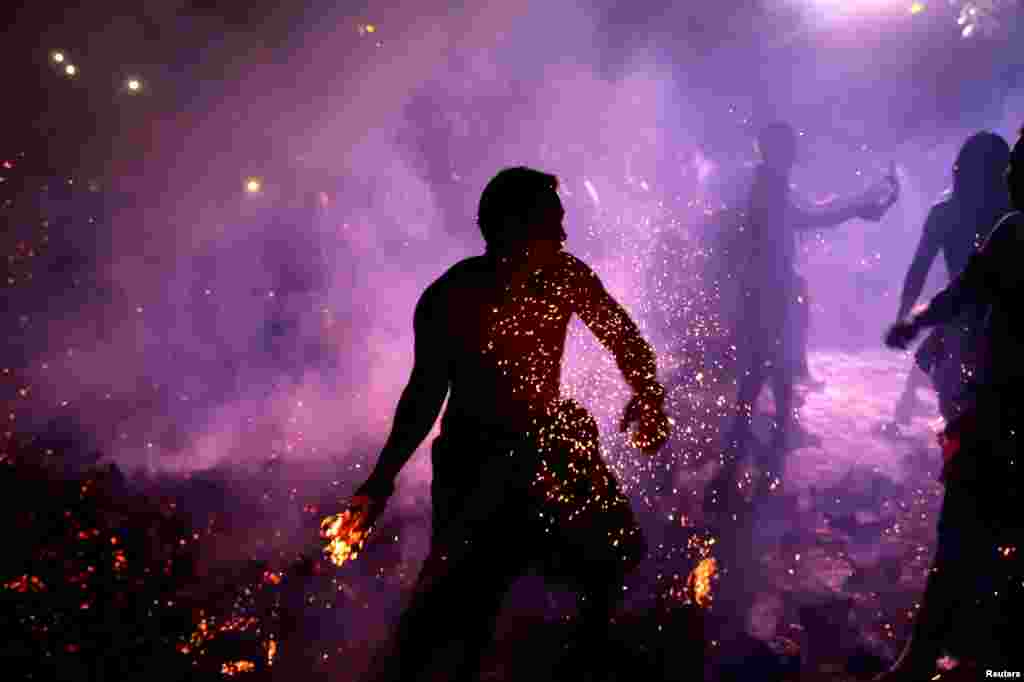 مردی اهل بالی اندونزی یک نارگیل آتشین را در جریان مراسم سنتی که برای ورود به سال نو هندو برگزار می&zwnj;شود، پرتاب می&zwnj;کند.
