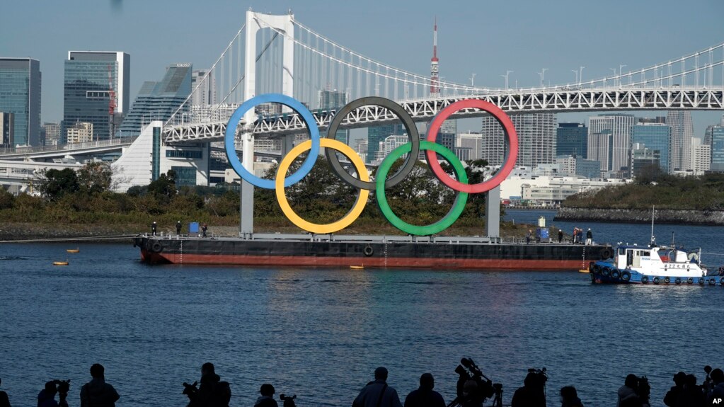 FILE - The Olympic Rings is put back up after they were taken down for repairs ahead of the postponed Tokyo 2020 Olympics in the Odaiba section of Tokyo, Tuesday, Dec. 1, 2020. (AP Photo/Eugene Hoshiko)