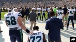 Seattle Seahawks' Michael Bennett remains seated on the bench during the national anthem before an NFL game against the Green Bay Packers, Sept. 10, 2017, in Green Bay, Wisconsin.